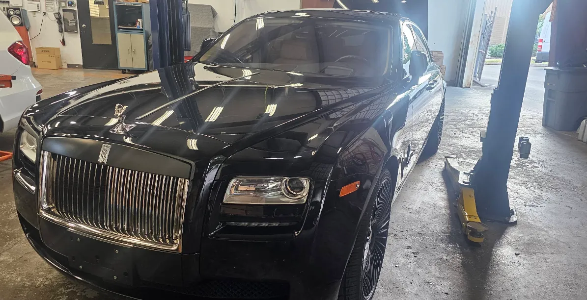 Black Rolls-Royce Ghost between lifts in the Lux Auto Centre service bay